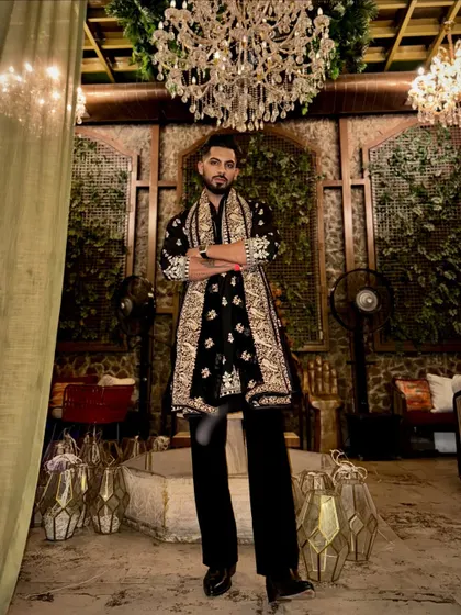 Standing under a grand chandelier, this outfit is right at home. The black kurta with its matching embroidered shawl creates a powerful and traditional look, perfect for a formal event.