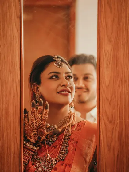 A creative shot of the bride looking in a mirror, her stained hand resting on the frame.