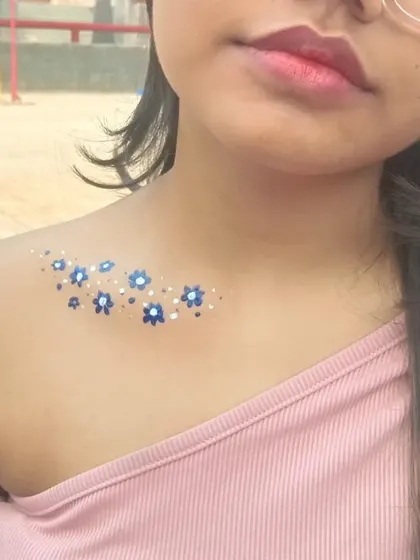 A constellation of tiny blue and white flowers painted on the shoulder, perfect for a subtle and dreamy look.