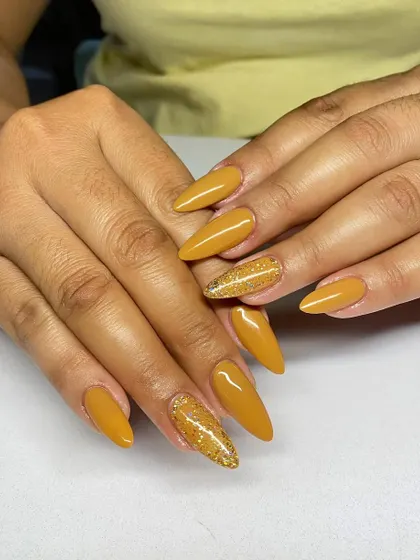 A warm and sunny set of almond-shaped extensions in a solid mustard yellow, with a gold glitter accent nail.