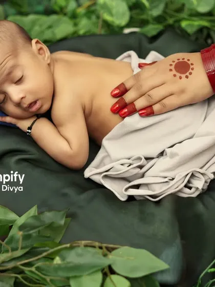 A sleeping newborn rests peacefully, watched over by the symbolic hands of Shiva and Parvati. This is a deeply meaningful concept for families welcoming a baby during Saavan.