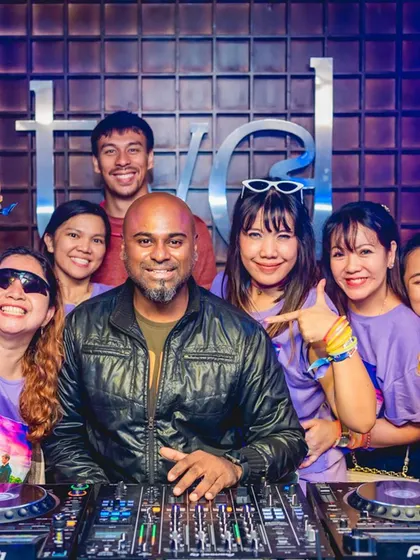 A group of fans in matching shirts at the DJ booth.
