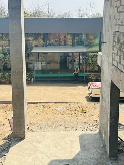 A view from the ground floor of the villa during construction, looking out. This shows the raw concrete columns and the connection to the outdoors that is central to the design.