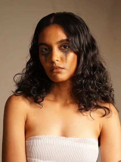 A raw, emotional portrait with smudged, glittery eye makeup to convey a story of vulnerability.