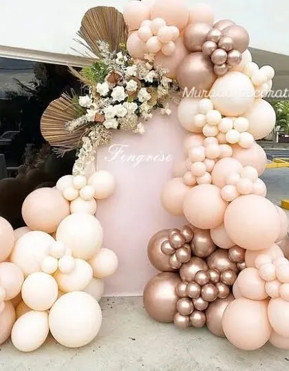 A beautiful balloon arrangement on a pale pink arched backdrop. I used a soft, romantic color scheme of blush, cream, and rose gold, with dried palm leaves and white flowers adding texture and elegance.