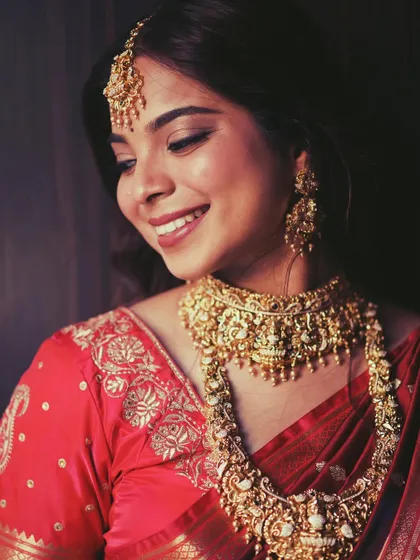 This bride is glowing in a traditional temple jewellery set. The layered necklaces and intricate choker, crafted in a rich gold finish, are perfect for a classic South Indian wedding ceremony.