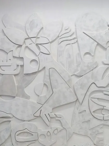 A detailed shot of the finished white plaster mural, showcasing the interplay of light and shadow across its varied surfaces and abstract shapes.