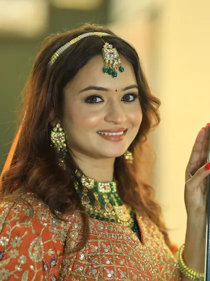 Elegance at its best. This bride is ready for her sangeet or reception in a beautiful orange lehenga with contrasting green jewelry.