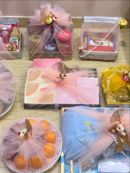 This image displays a variety of packed items for a bride, including clothing, fruits, and snacks. The consistent pink and gold theme ties everything together beautifully.