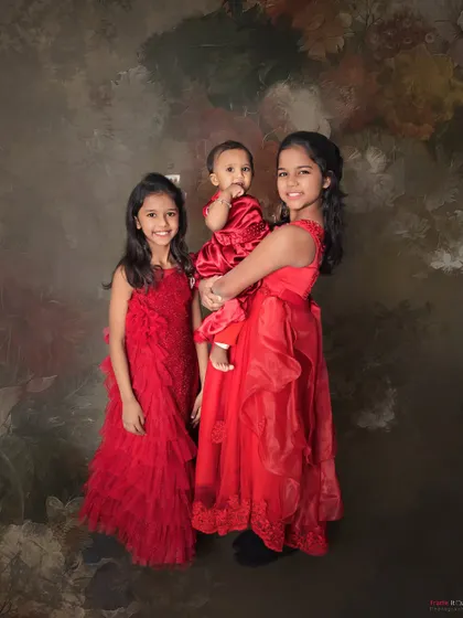 The sister bond is forever. These three sisters look beautiful in their matching red dresses, creating a classic and elegant portrait.
