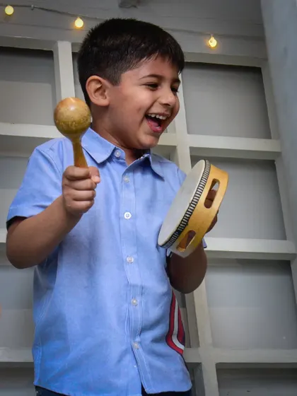 Making some noise! This happy boy plays the maraca and tambourine, adding to the festive music of the party.