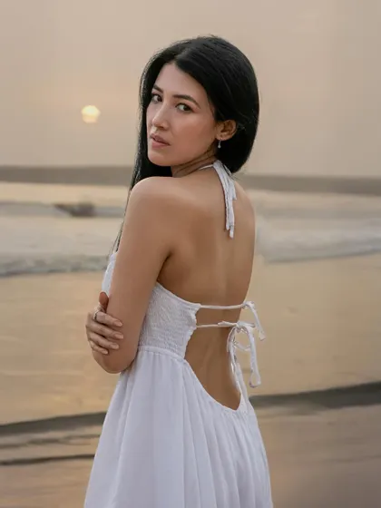 A serene golden-hour portrait of a woman on a beach, looking over her shoulder with the sun setting over the ocean. This image highlights my ability to capture natural beauty and emotion in outdoor settings.