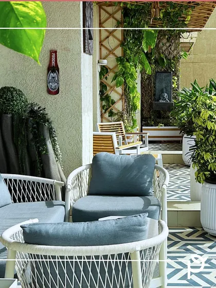 A comfortable seating arrangement on a balcony with patterned flooring. We used a combination of planters and a trellis with climbers to create a lush, green backdrop for this outdoor lounge area.