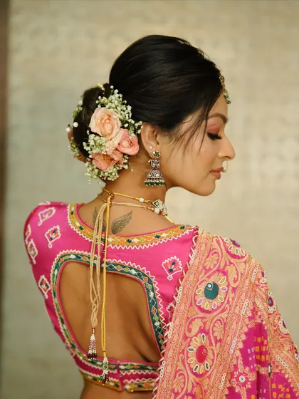 The back view of this royal pink lehenga, showing the elegant low bun adorned with fresh flowers. This hairstyle is perfect for keeping the hair off the face while looking incredibly graceful.