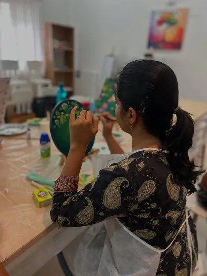 A participant deeply focused on her Koi Fish painting. The detailed work is meditative and rewarding.