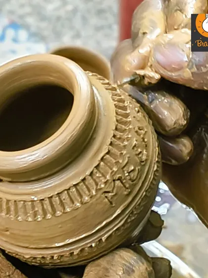 A close up of a freshly thrown pot on the wheel, showing the texture and detail added by a young potter.
