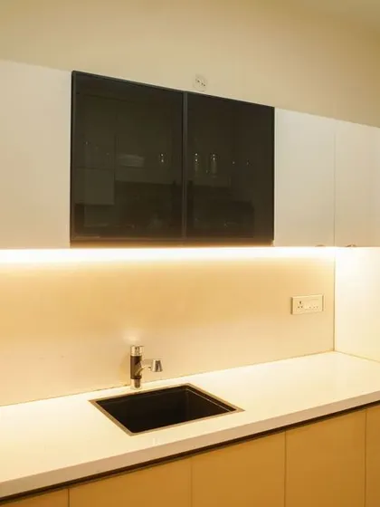 A look at the cooking side of the parallel kitchen, with a black sink and dark glass-fronted upper cabinets that add contrast. The design is a perfect example of modern, space-saving solutions.