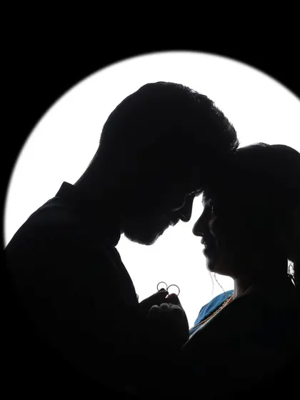 A creative silhouette of the couple holding their engagement rings, a unique and artistic way to announce their commitment.