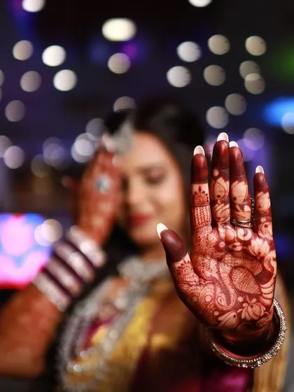 Another artistic shot with a shallow depth of field, drawing the viewer's eye directly to the intricate details of the stained mehendi on the bride's palm.