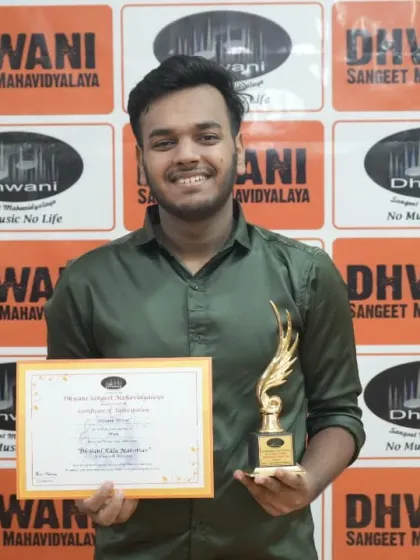 A young man proudly holds his certificate and trophy for his musical performance.