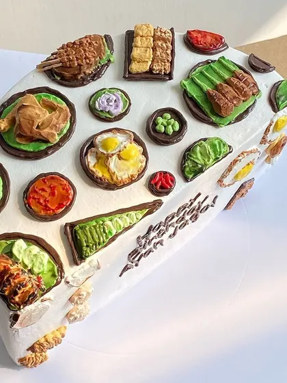 A fan-shaped cake decorated with a variety of Indonesian grilled and fried dishes, demonstrating creative shaping and detailed food modeling.
