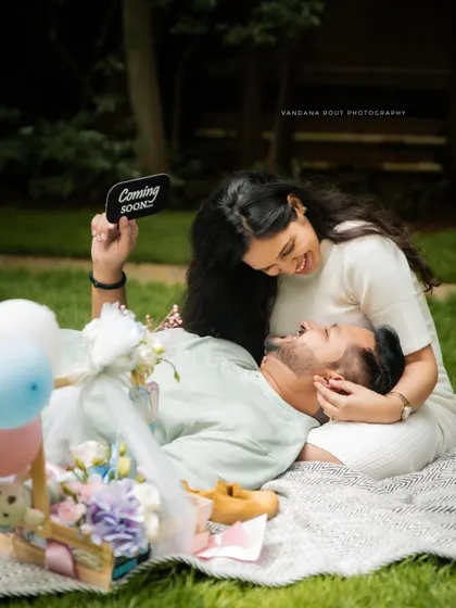 A sweet picnic setup where the couple shares a laugh. The "Coming Soon" sign adds a cute and clear announcement to their maternity photos.
