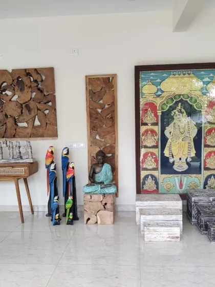 A display of various decorative items, including wooden parrot statues, a Buddha on a wooden block, and traditional Indian paintings.