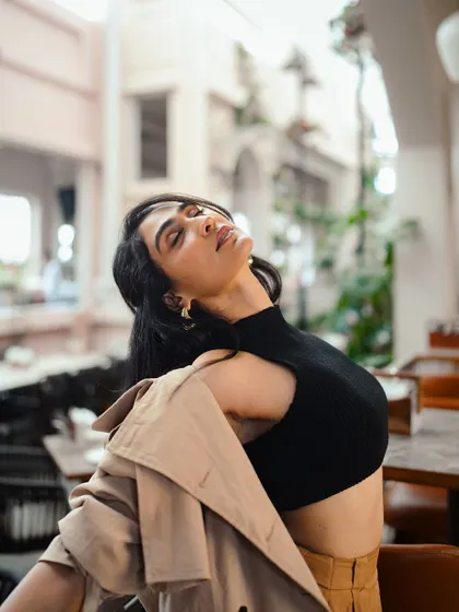 This shot captures a feeling of freedom and relaxation. The simple, well-fitting black crop top is a wardrobe staple that can be dressed up or down.