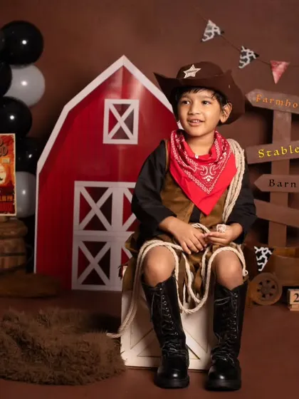 A thoughtful moment for our little cowboy, sitting proudly in his full western outfit during his fourth birthday shoot.
