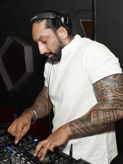 A close-up of me working the mixer, showing my tattooed arm. My personal style is part of my brand, bringing a cool and modern edge to my performance.