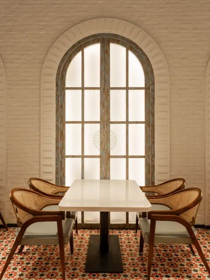 The large arched window with its distressed wood finish adds a touch of rustic charm and architectural interest to the dining space.