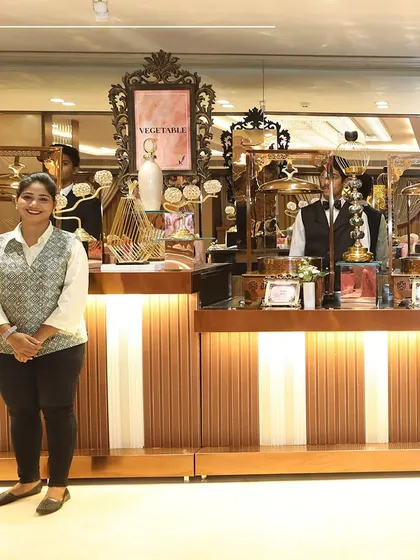 Our skilled culinary artisans take pride in crafting flavours that delight the senses. A member of our service team stands ready at an elegant buffet station.