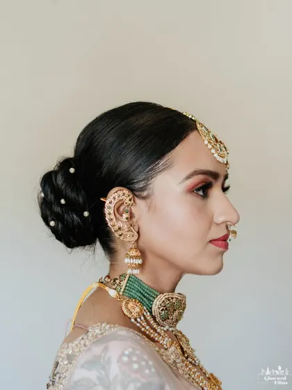 A side profile of the bride, Sanskaara, showing off her elegant braided bun and traditional jewelry.
