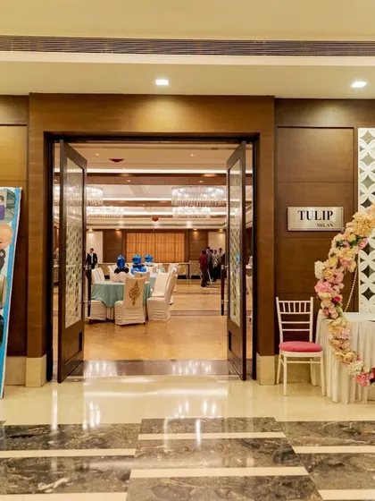 The entrance to the party hall is the first impression. Here, I set up a custom photo collage standee showing the family's journey, along with a beautiful floral ring for guests to take pictures as they walked in.