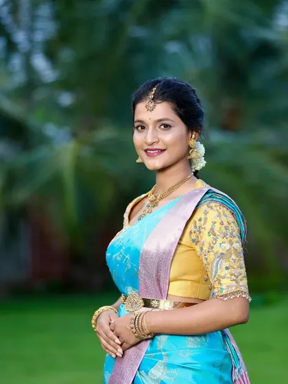 The beautiful bride-to-be Kavya glows in a sky-blue designer silk saree for her engagement. Paired with a contrasting yellow embroidered blouse, this look is both vibrant and traditionally elegant.