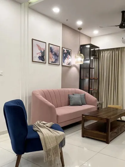 A living room design that plays with color, pairing a soft pink sofa with a bold blue accent chair against a two-toned wall.