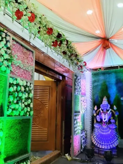 This entrance to a ceremony features a colorful flower wall and statues of deities, creating a vibrant and sacred passage.