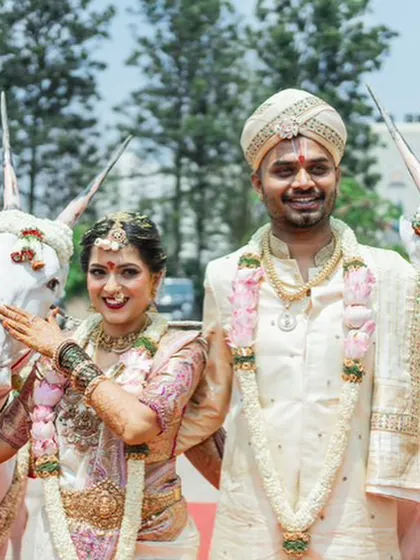 A joyful moment from a wedding procession. The groom's custom silk couture and the bride's matching ensemble shine even in the bright daylight.