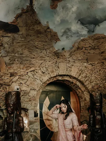This portrait has a mystical, cavern-like feel. The bride is framed by a stone arch, with dramatic lighting and a unique, artistic ceiling, creating a one-of-a-kind image.