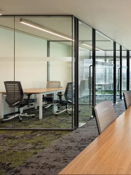 We create a variety of work settings within a single office. This image shows a glass-walled meeting room adjacent to an open workstation area, providing acoustic privacy for meetings while maintaining the visual openness of the overall layout.