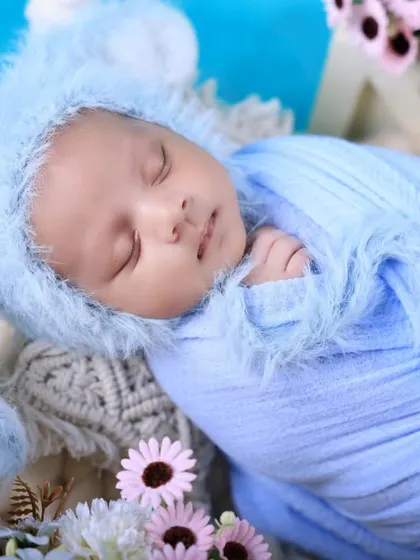 This newborn looks adorable in a fuzzy blue bunny bonnet. We use soft, comfortable wraps and cute accessories to style your baby for their first photoshoot.