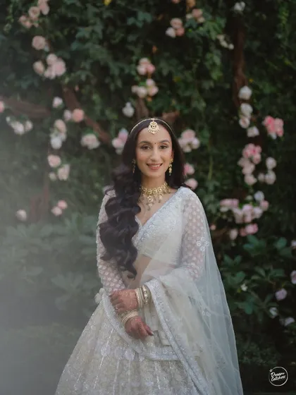 A classic bridal portrait against a backdrop of flowers, capturing the bride's happy and gentle smile.