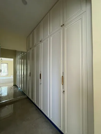 Closets so sleek, even my secrets want to hide in style! A full wall of classic white wardrobes providing ample, elegant storage.