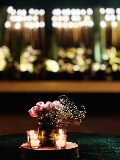 An artistic, soft-focus shot of a candle-lit centerpiece, with the beautifully lit Sangeet stage blurred in the background.