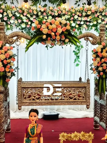 For a timeless naming ceremony, I designed this elegant floral cradle setup. The beautifully carved wooden cradle is adorned with fresh peach and white roses, creating a serene and classic centerpiece for the special day.