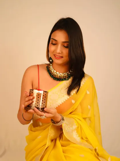 This shot captures a candid moment from a festive photoshoot, showing the model interacting with a decorative candle holder, adding a lifestyle feel.