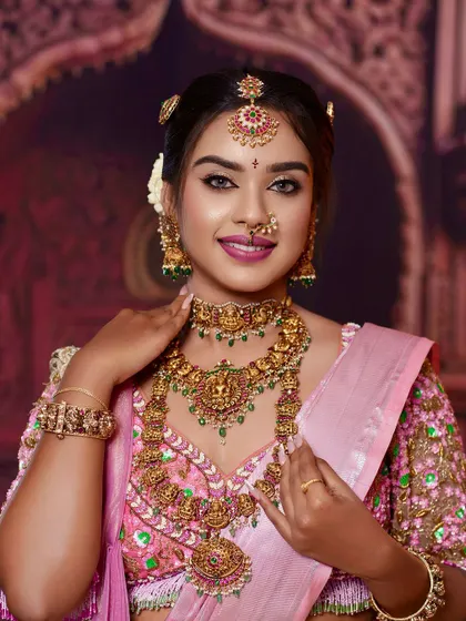 A close-up view of our signature temple jewellery. You can see the intricate carvings of deities and the fine detailing with green and red stones, perfect for a traditional South Indian bride.