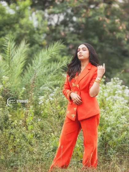 A full-length shot of the orange bee-embroidered suit, showcasing its flattering wide-leg pants.