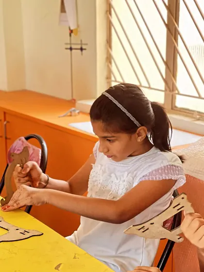 This student is focused on assembling the frame of a wooden model, learning about structure and design.