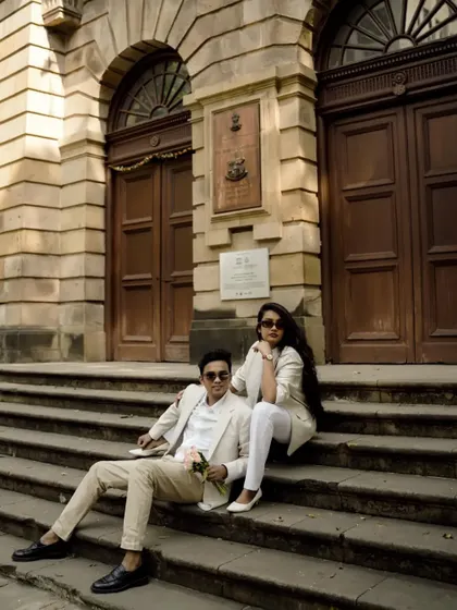 A stylish, modern pre-wedding shoot in Mumbai. The couple's coordinated white outfits look sharp against the classic stone architecture.